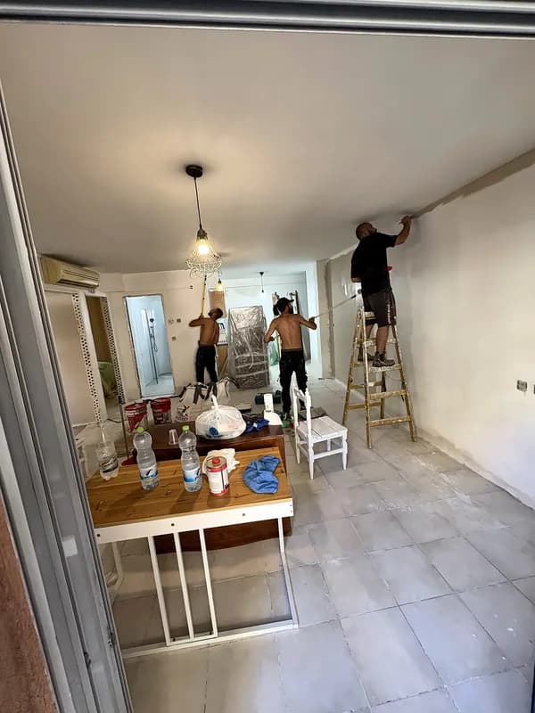 צוות בעבודות צבע על סולמות בסלון