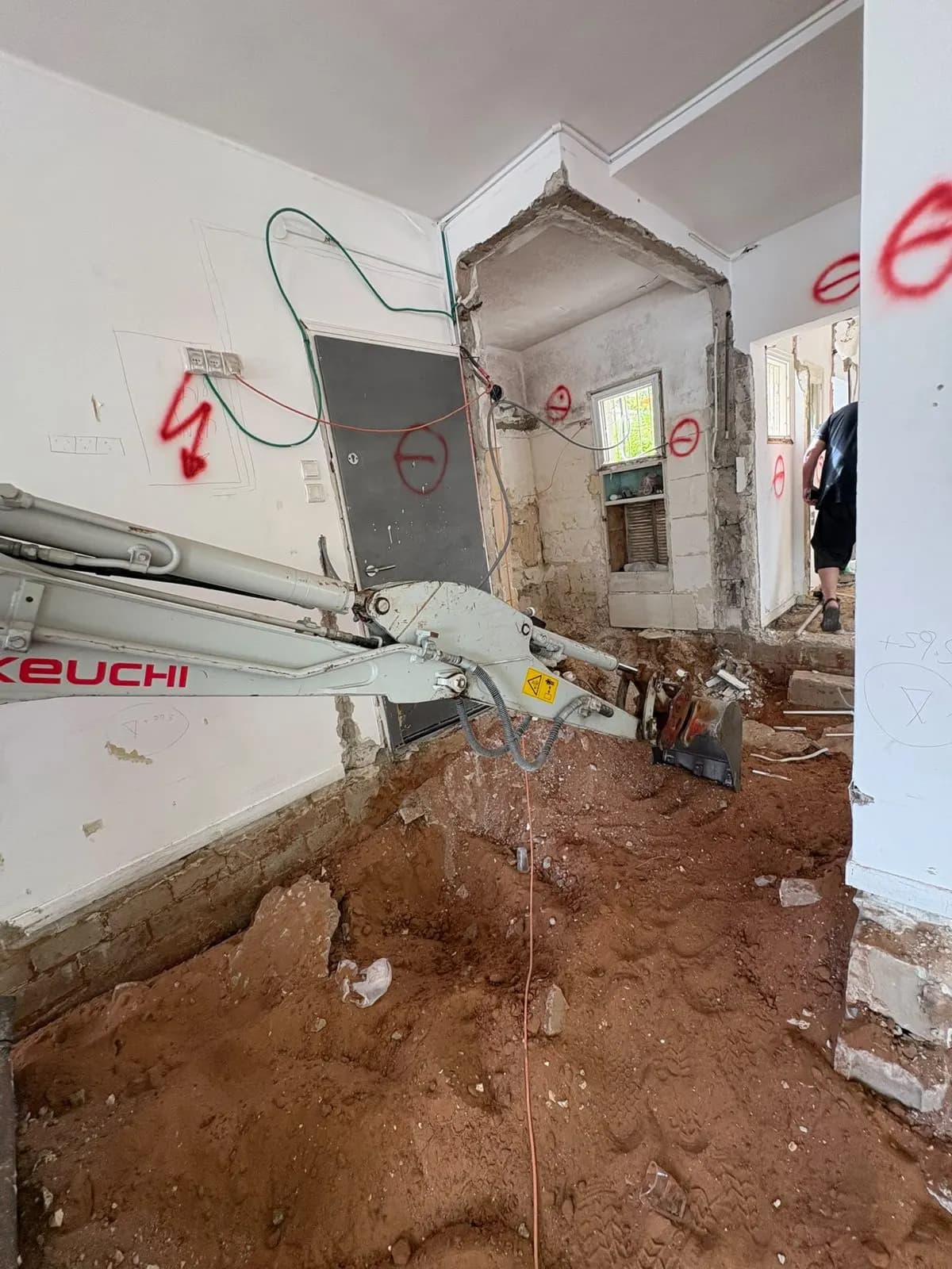 הריסה בתוך הבית: מחפרון קטן, אדמה חפורה וקירות פתוחים